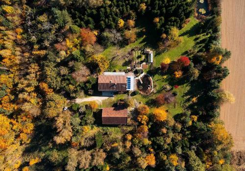Das Grundstück aus der Vogelperspektive mit Blick auf Scheune, Haus, Teiche und Wald