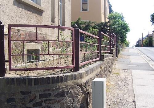 Natursteinmauer mit Eisenzaun