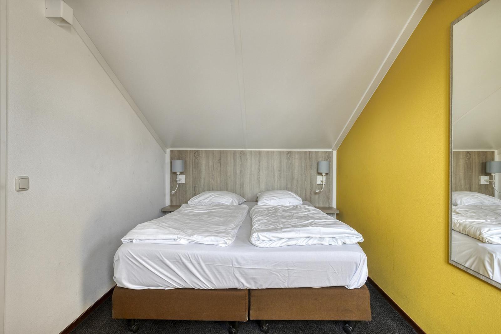 hauptschlafzimmer-kaufen-duinresort-gelbe-wand-doppelbett01