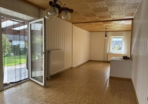 Das Wohnzimmer mit Tür zur Terrasse und den Garten