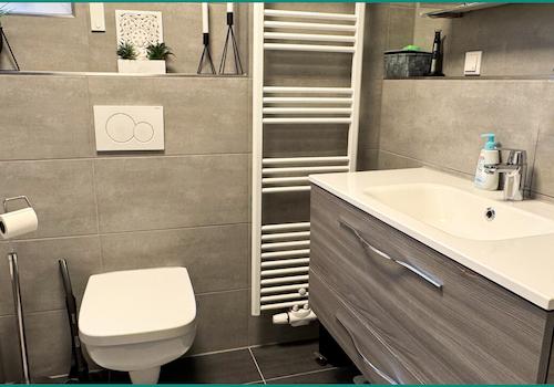 Modernisiertes Badezimmer mit Fenster und Handtuchheizkörper und...