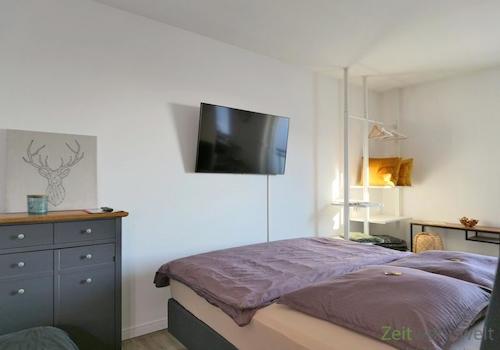 Doppelbett und TV hinter dem Raumteiler