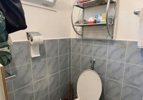 Lichtdurchflutetes Gäste-WC mit praktischem Wandregal und elegantem Fliesenspiegel - (KI generiert)