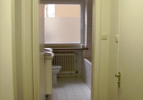 Ansicht Badezimmer vom Flur mit Gäste-WC Türe rechts
