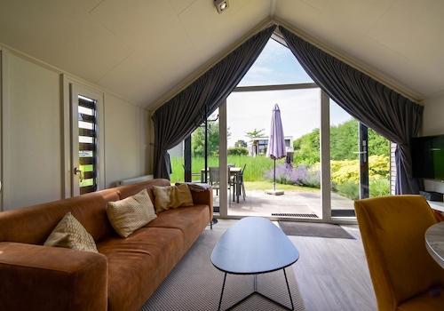 kaufen-freistehendes-ferienhaus-olburgen-wohnzimmer-hohe-decke-und-gartenblick-recreatieadviseurs-vakantiehuistekoop-nl.jpg