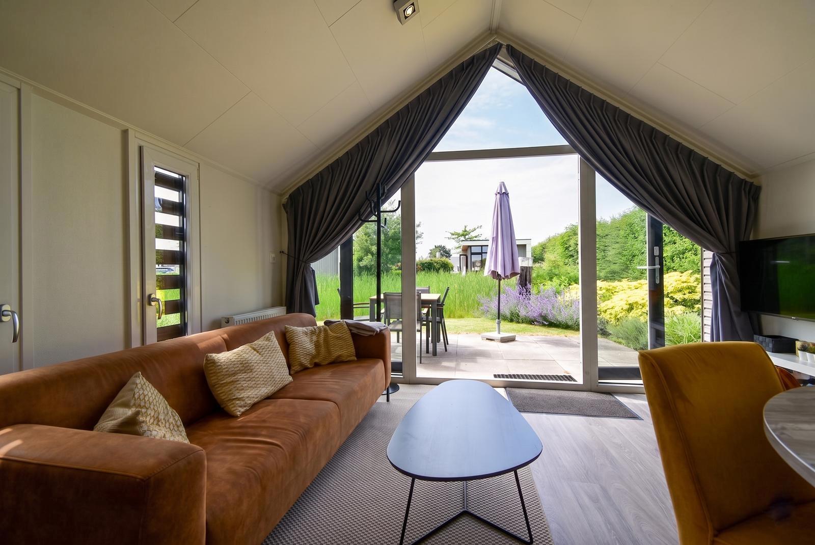 kaufen-freistehendes-ferienhaus-olburgen-wohnzimmer-hohe-decke-und-gartenblick-recreatieadviseurs-vakantiehuistekoop-nl.jpg