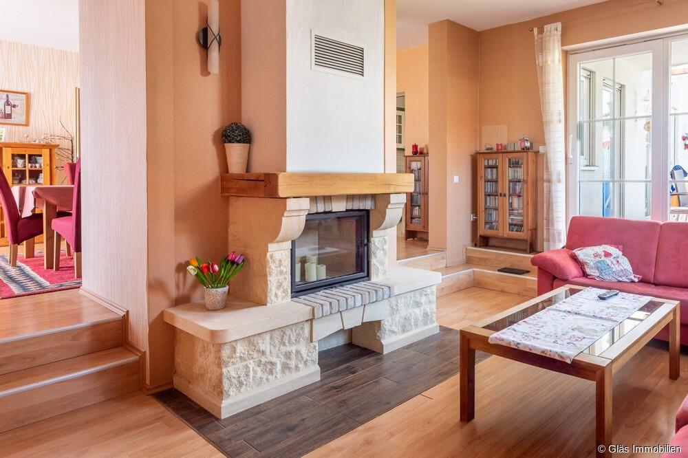 Wohnzimmer mit Kamin und Zugang zur überdachten Terrasse