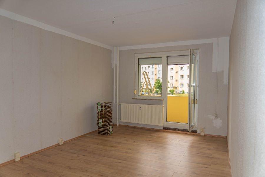 Stube mit Balkon und Laminatboden.