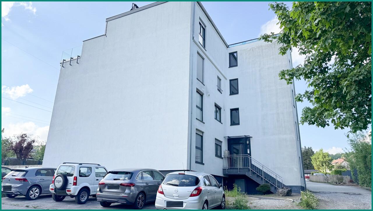 Ansicht der Gebäudeseite mit Zugang und Parkplätzen