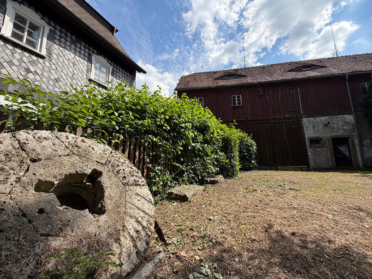 altes Mühlrad mit Blick auf die Scheune