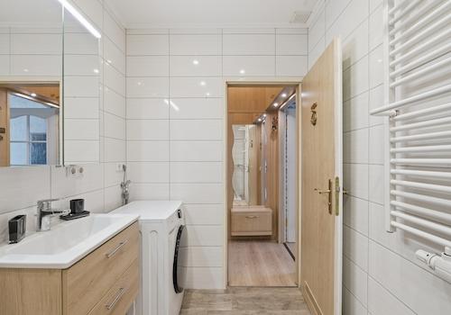 Badezimmer mit breitem Waschtisch, Waschmaschine und Handtuchheizung