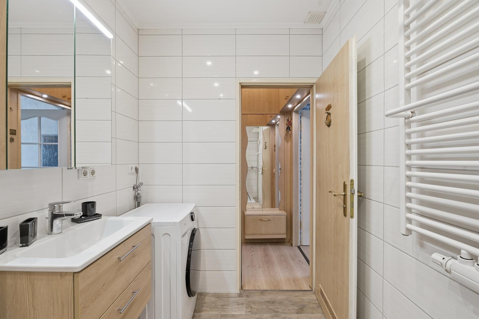 Badezimmer mit breitem Waschtisch, Waschmaschine und Handtuchheizung