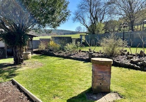 KI-generiert: schön angelegter Garten direkt am Feldrand