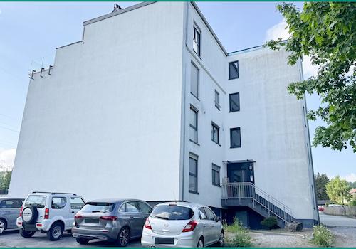 Ansicht der Gebäudeseite mit Hauszugang und Parkplätzen