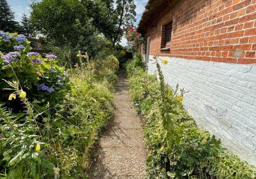 Seitlicher Gartenweg entlang der Backsteinfassade
