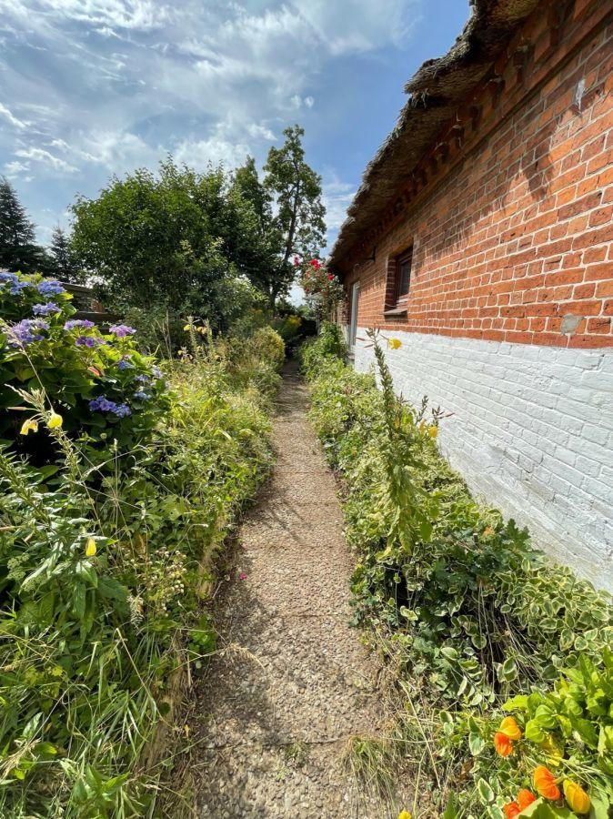 Seitlicher Gartenweg entlang der Backsteinfassade
