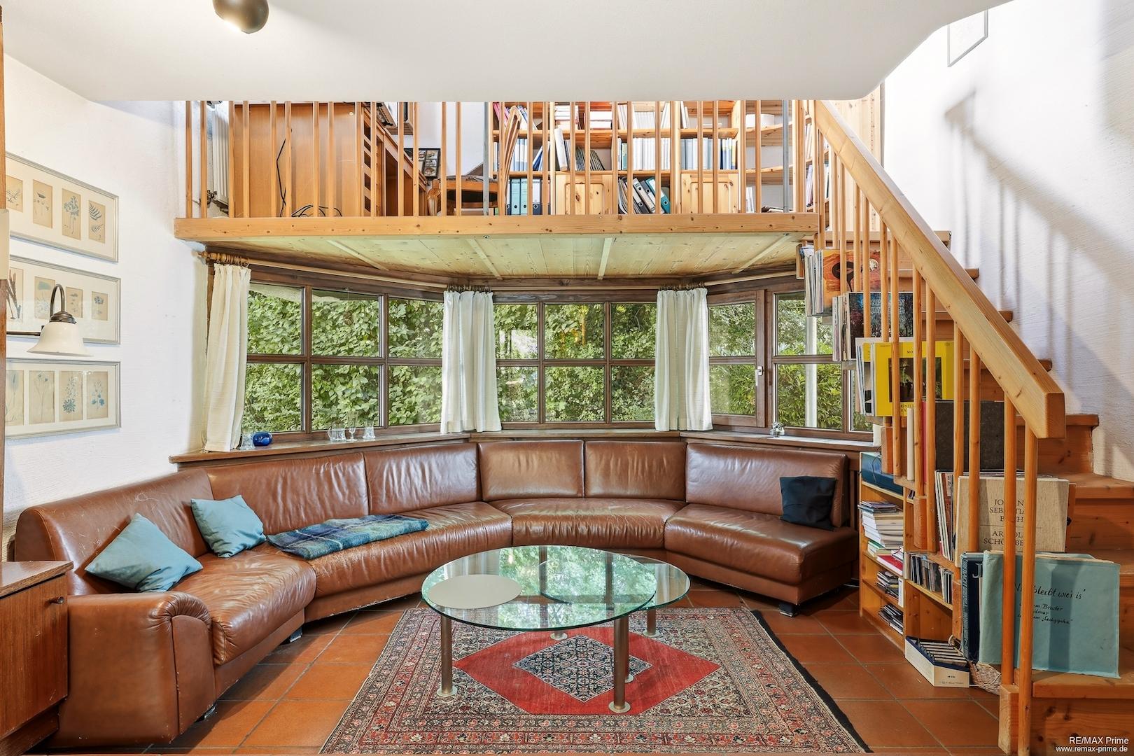 Wohnbereich mit Blick auf Park, über der Lounge-Couch befindet sich die Galerie