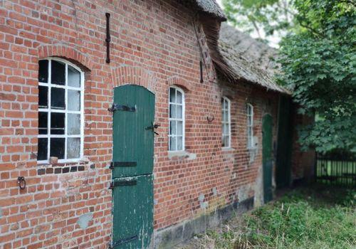 Backsteinfassade mit historischen Fenstern und Seiteneingang