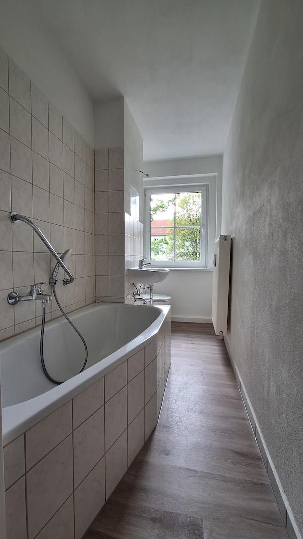 gefliestes Bad mit Wanne und Fenster